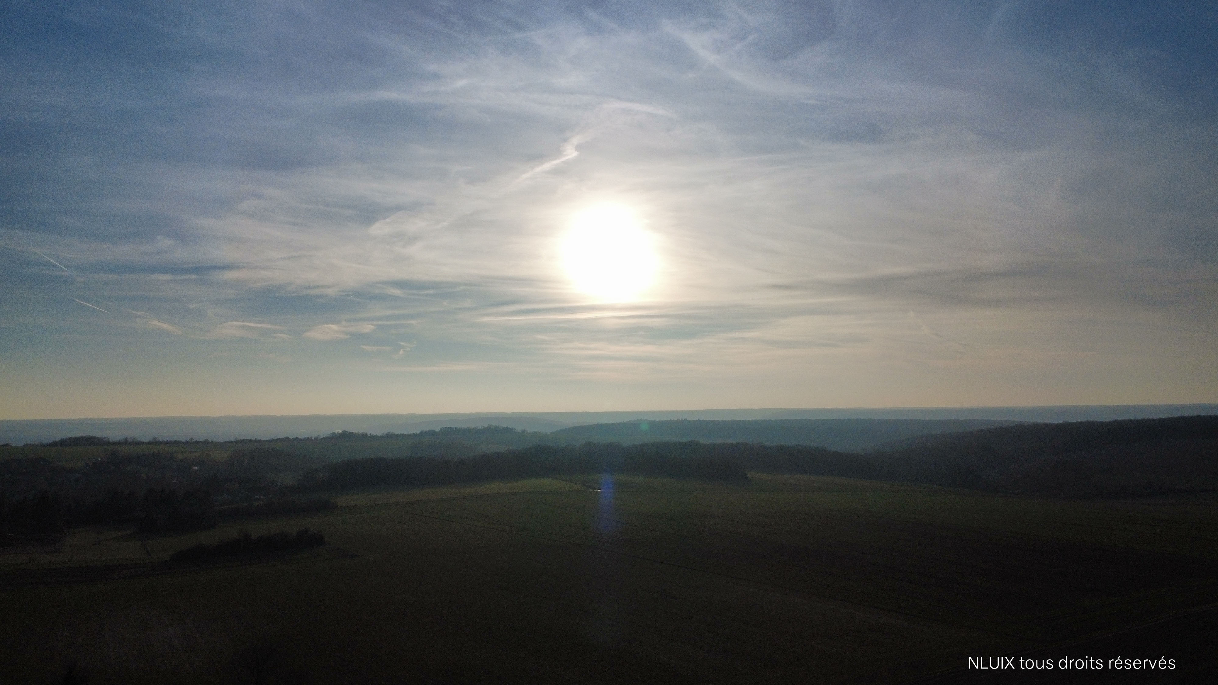 Photo avec un soleil couchant et des traits nuages. 